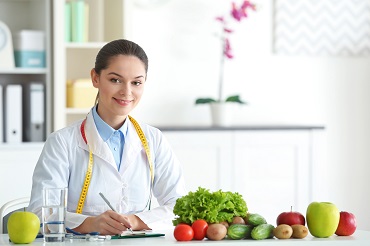 Female Nutritionist sitting at a table next to veggies