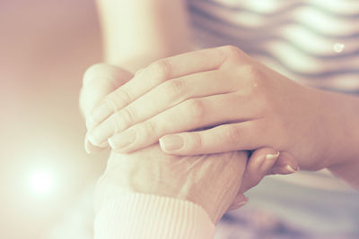 A woman is holding an elderly woman's hand