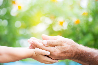 Female has her hands out and an elderly man has his hands placed on top of hers.